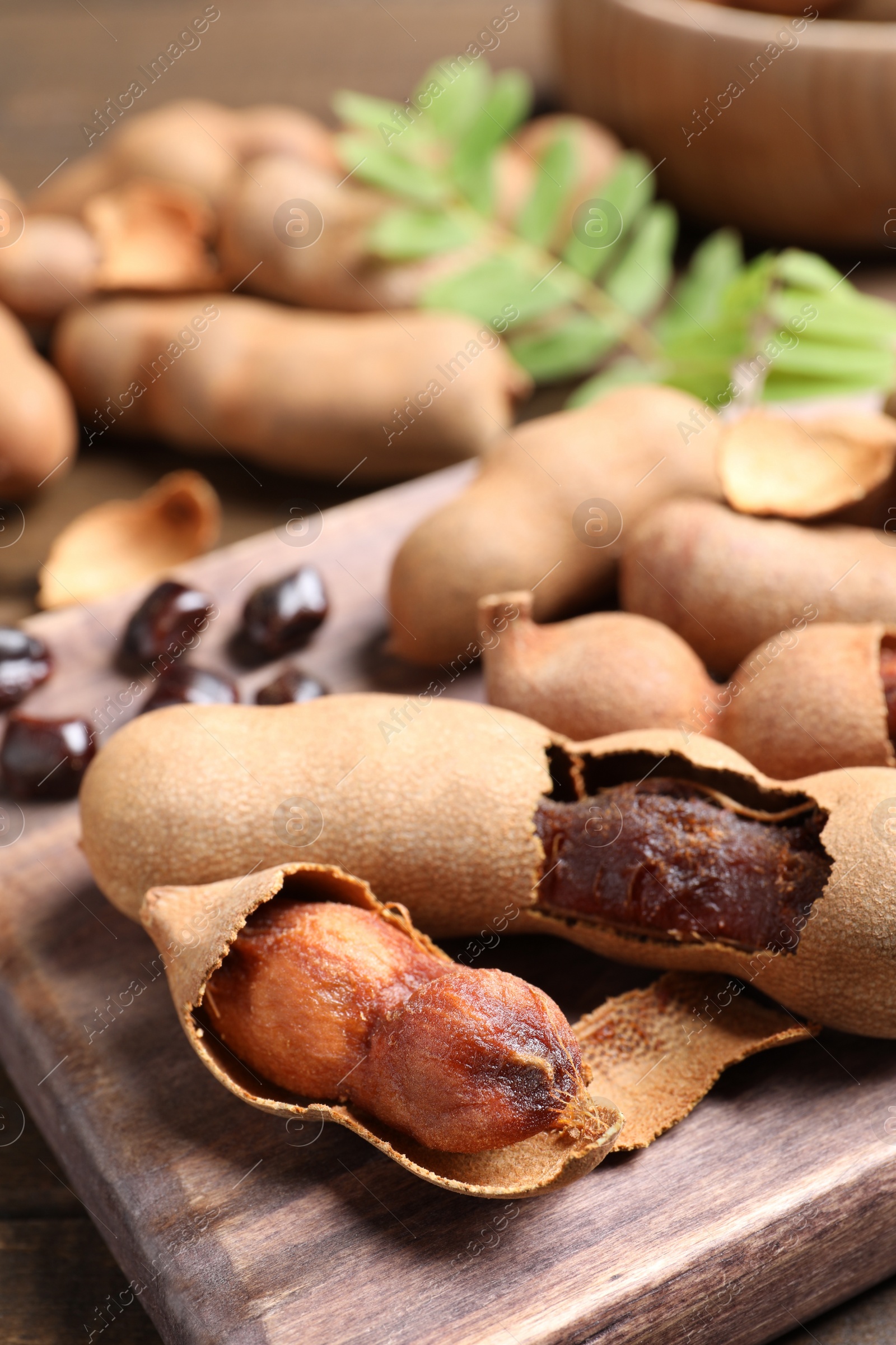 Photo of Delicious ripe tamarinds on wooden board, closeup