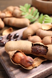 Photo of Delicious ripe tamarinds on wooden board, closeup