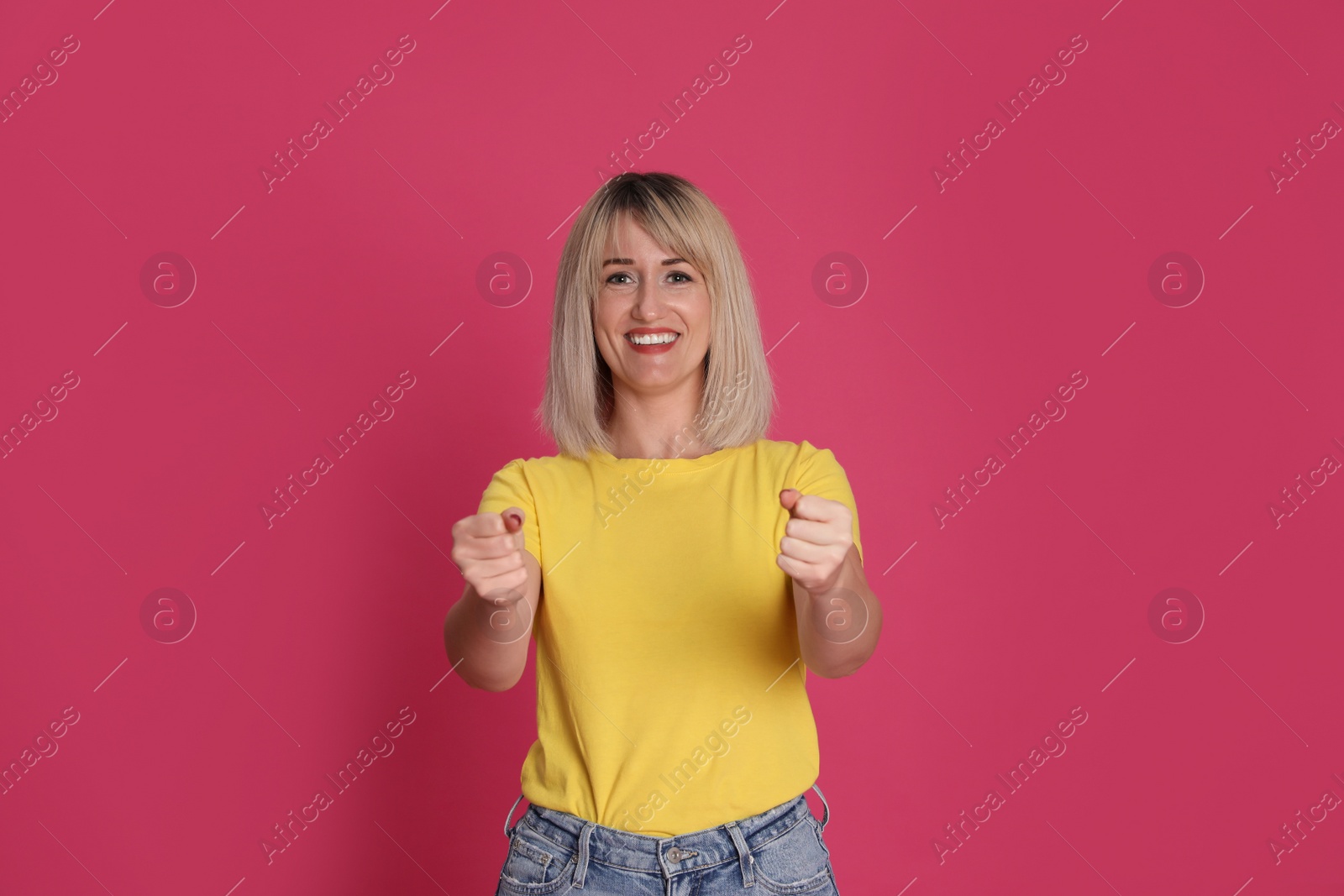 Photo of Happy woman pretending to drive car on crimson background