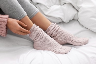 Woman wearing warm socks in comfortable bed, closeup