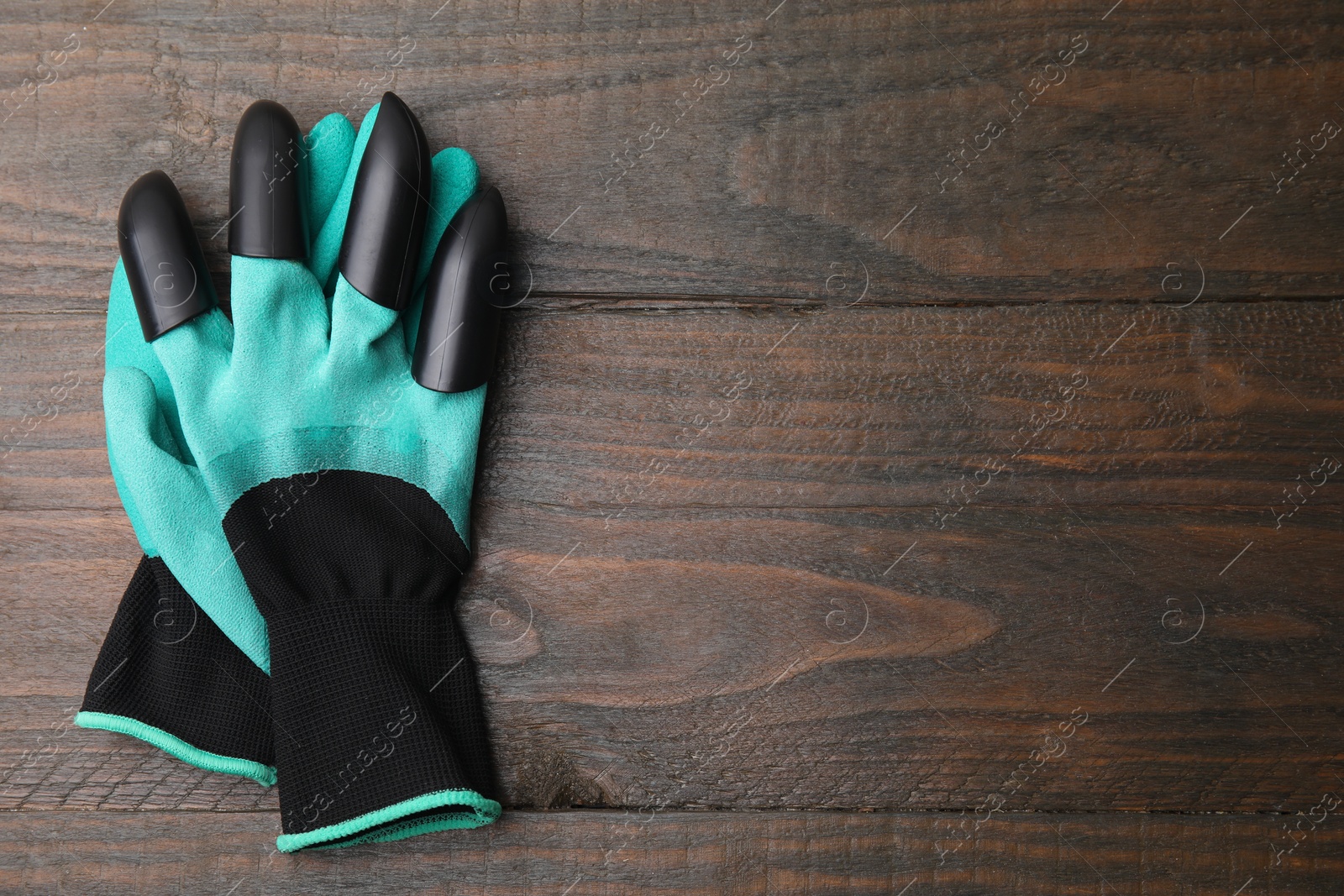 Photo of Pair of claw gardening gloves on wooden table, top view. Space for text