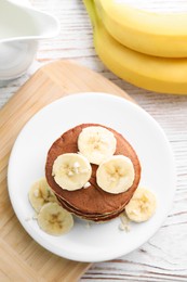 Plate of banana pancakes on white wooden table, flat lay