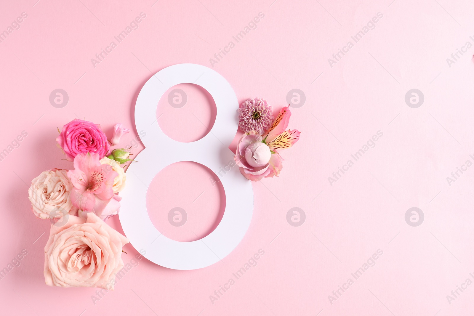 Photo of 8 March greeting card design with beautiful flowers on light pink background, top view