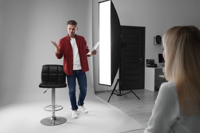 Photo of Man with script performing in front of casting director against light grey background in studio