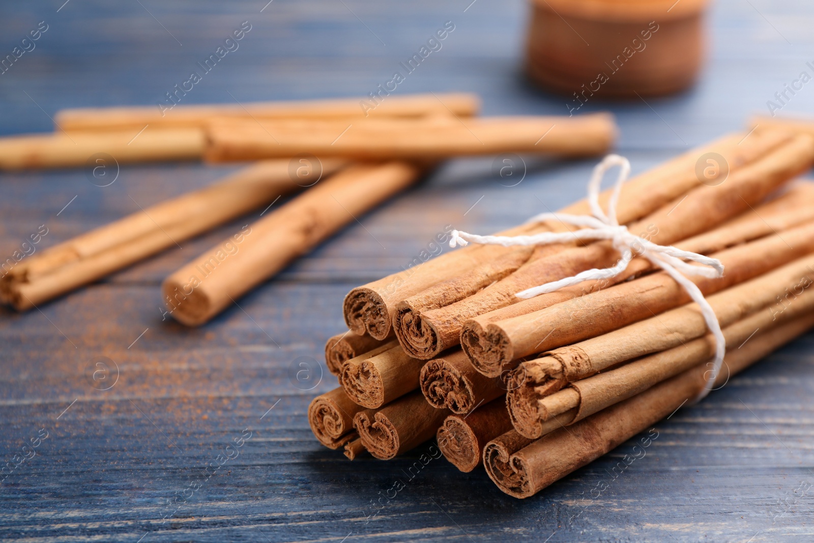 Photo of Aromatic cinnamon sticks on blue wooden table, closeup. Space for text