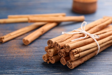 Photo of Aromatic cinnamon sticks on blue wooden table, closeup. Space for text