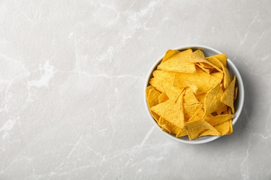 Photo of Tasty mexican nachos chips in bowl on grey table, top view. Space for text