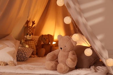 Photo of Play tent with toys and pillows indoors, closeup. Modern children's room interior