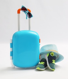 Photo of Composition with blue suitcase and child accessories on white background. Summer vacation
