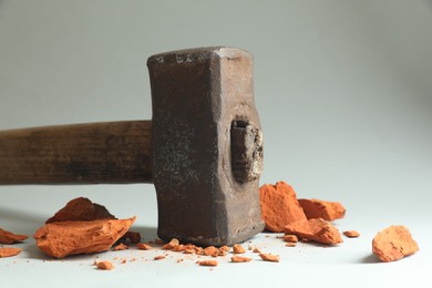 Photo of One sledgehammer and pieces of broken brick on grey background, closeup