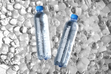 Photo of Bottles of water on ice cubes, flat lay