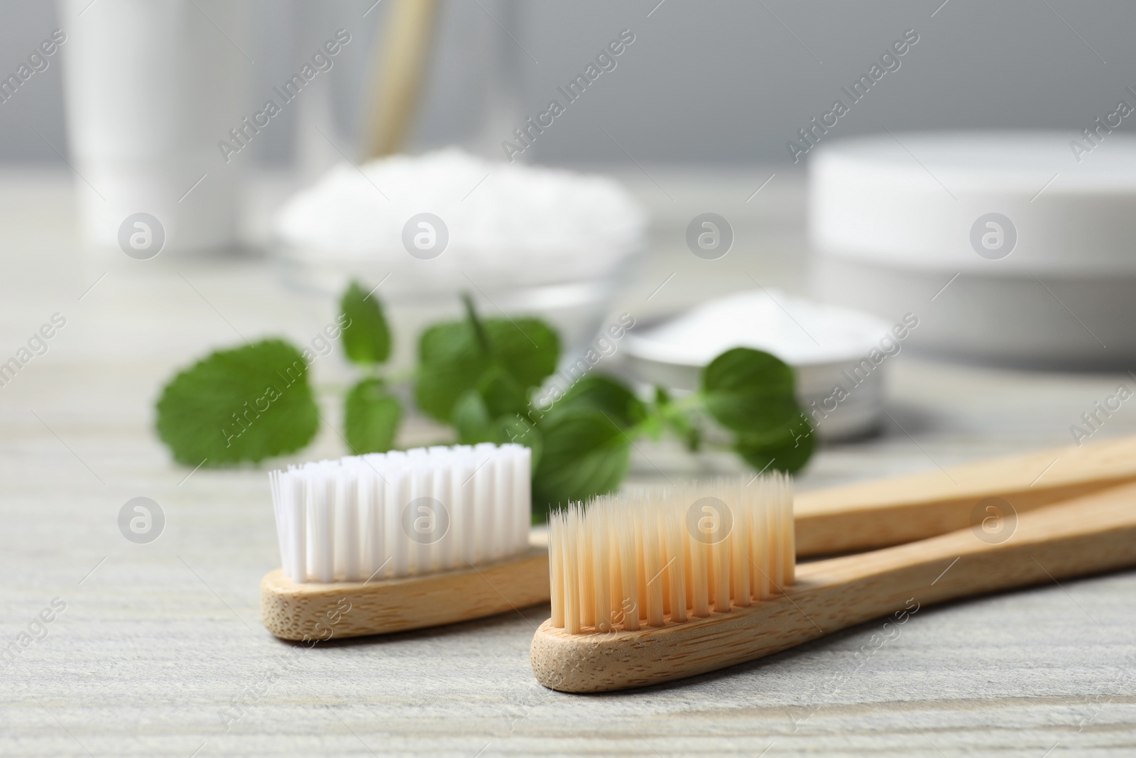 Photo of Toothbrushes and green herbs on wooden table, closeup