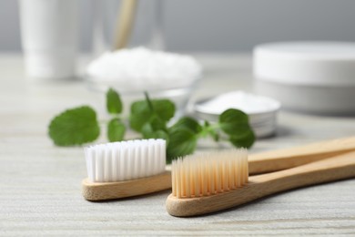 Toothbrushes and green herbs on wooden table, closeup