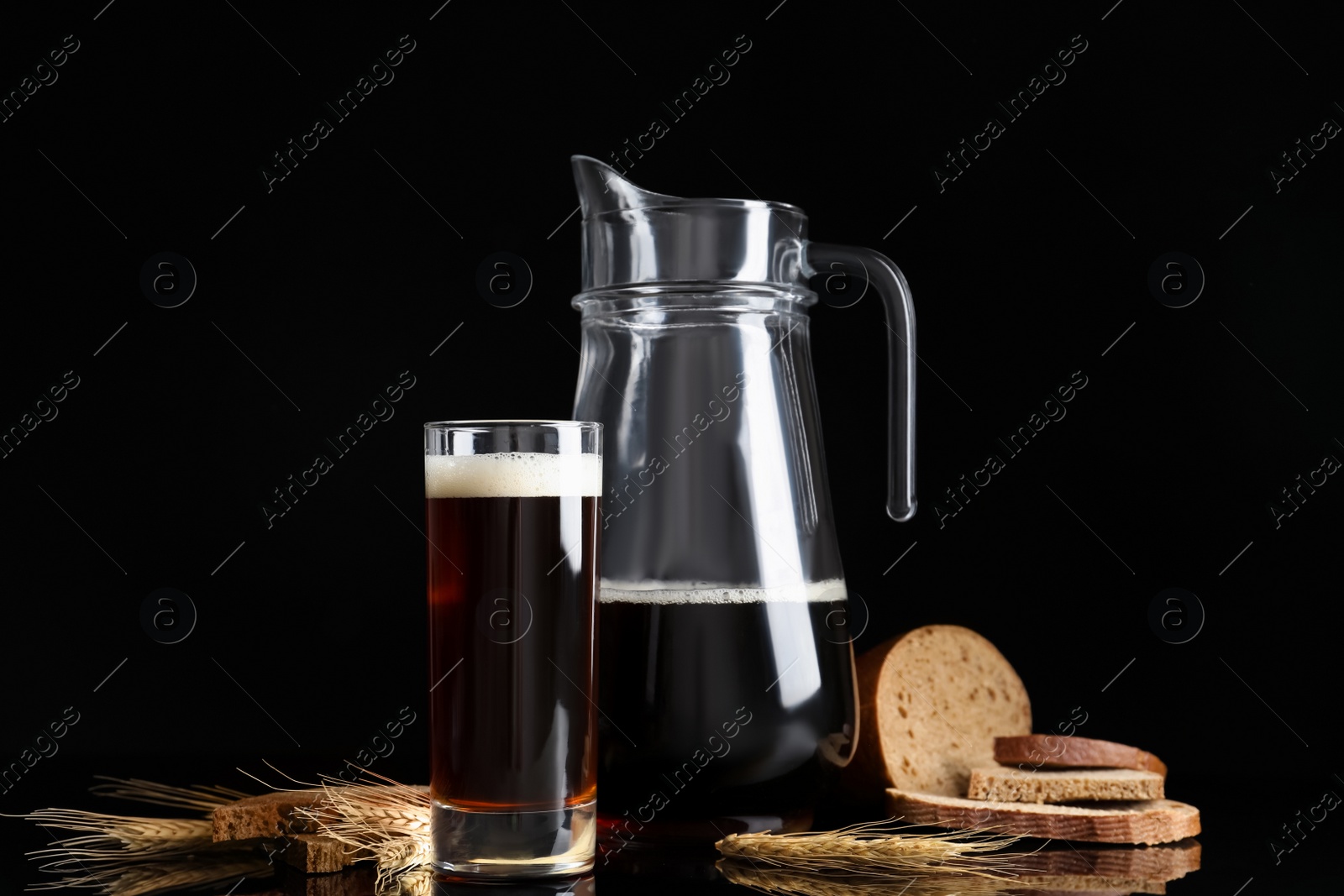 Photo of Delicious kvass, bread and spikes on black background