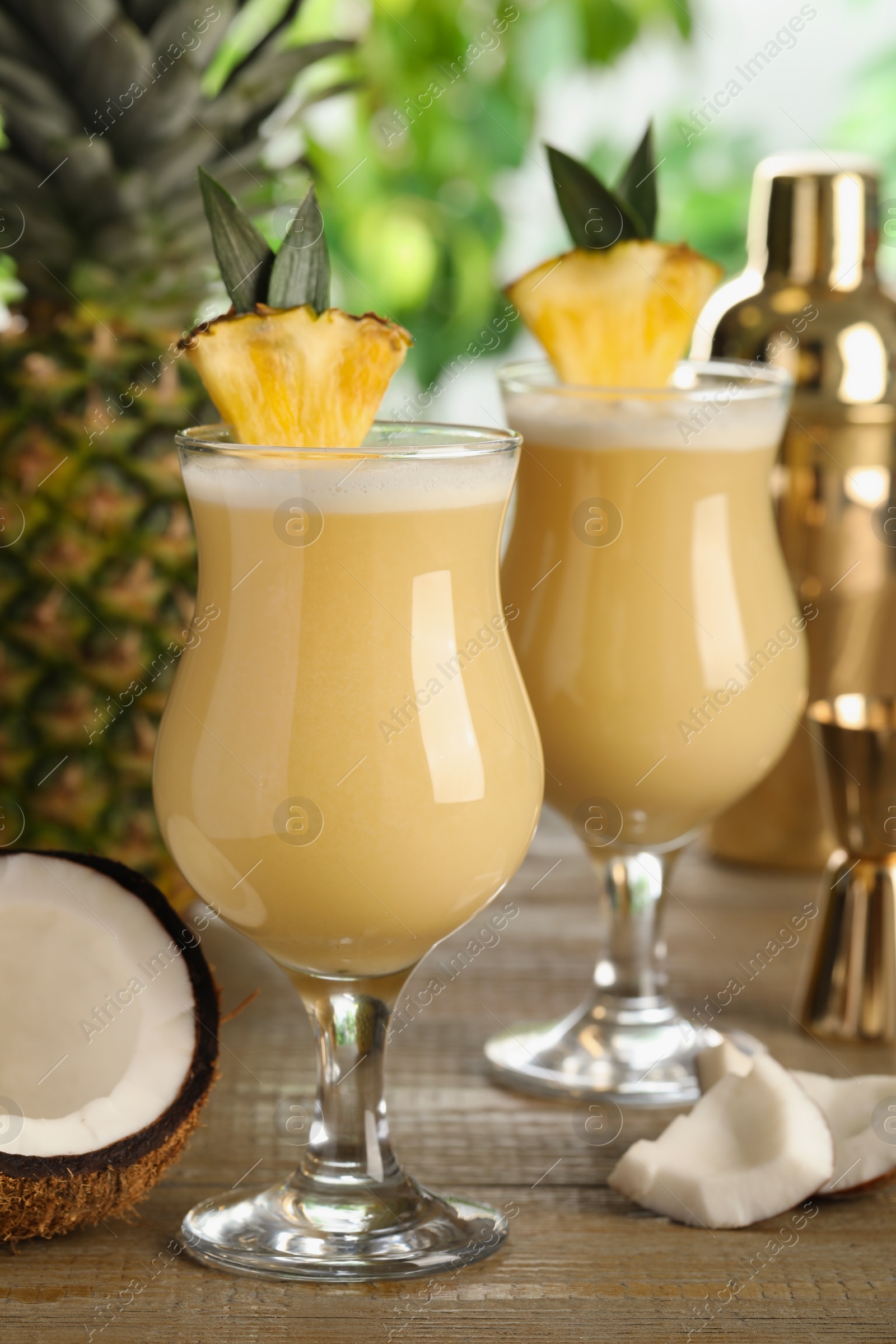 Photo of Tasty Pina Colada cocktails and ingredients on wooden table