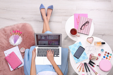 Photo of Beauty blogger with laptop and cosmetics sitting on floor, top view