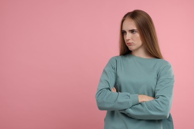 Resentful woman with crossed arms on pink background, space for text