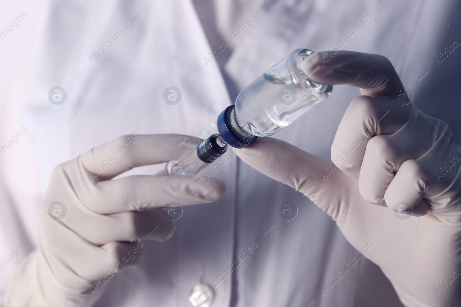 Photo of Doctor filling syringe with vaccine from vial, closeup