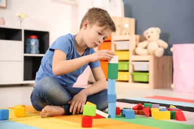 Little autistic boy playing with cubes at home