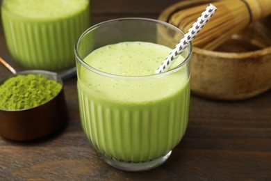 Photo of Glass of tasty matcha smoothie and powder on wooden table, closeup