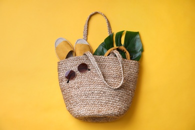 Photo of Stylish straw bag and summer accessories on yellow background, flat lay