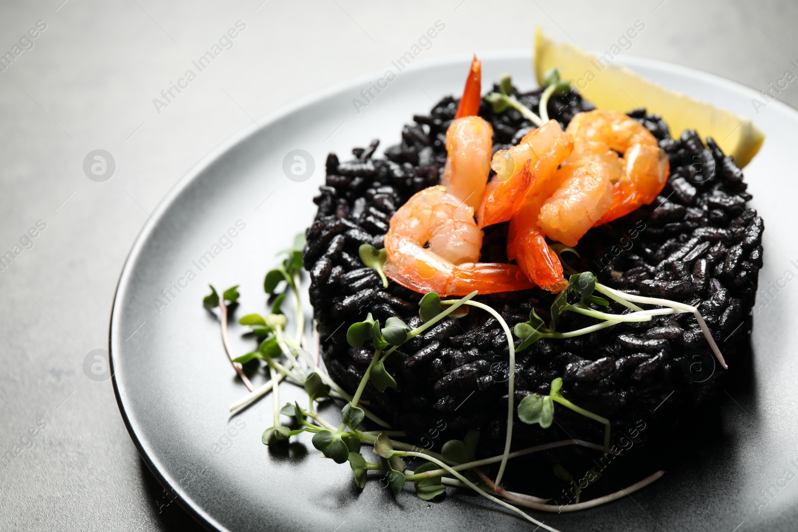 Photo of Delicious black risotto with shrimps on grey table, closeup