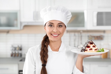 Professional female chef with plate of delicious dessert in kitchen