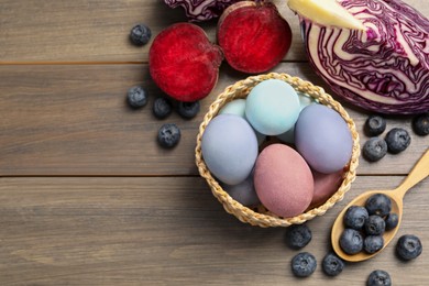 Photo of Colorful Easter eggs painted with natural dyes and ingredients on wooden table, above view