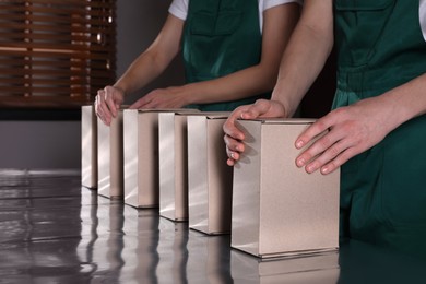 People packing cardboard boxes at production line indoors, closeup