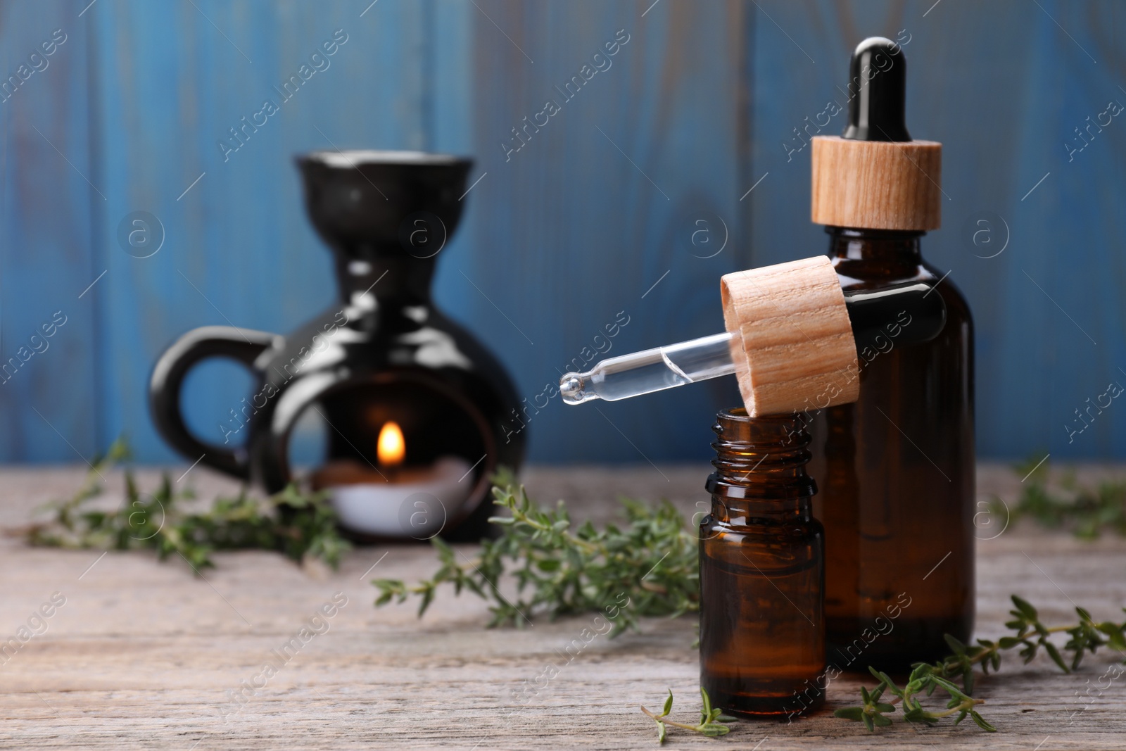 Photo of Thyme essential oil and fresh plant on wooden table, space for text