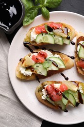 Delicious bruschettas with balsamic vinegar and toppings on table, flat lay