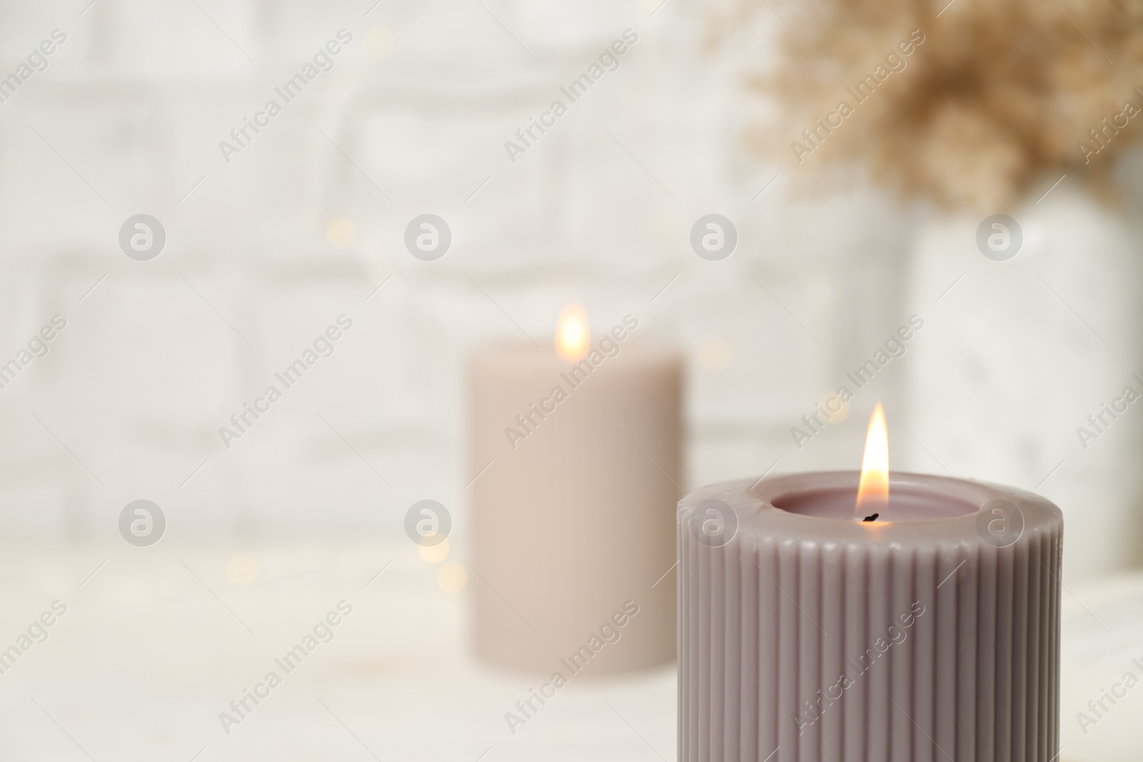 Photo of Burning candle on blurred background, closeup. Space for text