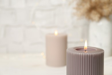 Burning candle on blurred background, closeup. Space for text