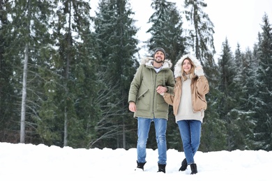 Photo of Couple near conifer forest on snowy day, space for text. Winter vacation