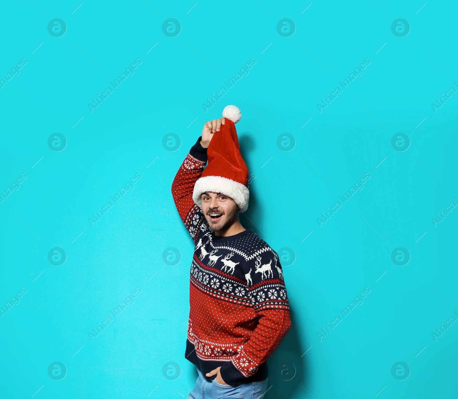 Photo of Young man in Christmas sweater and hat on color background