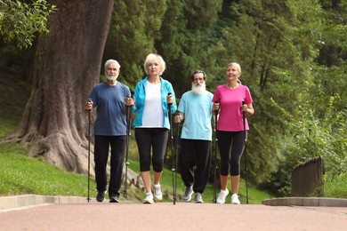 Photo of Group of senior people performing Nordic walking outdoors. Low angle view