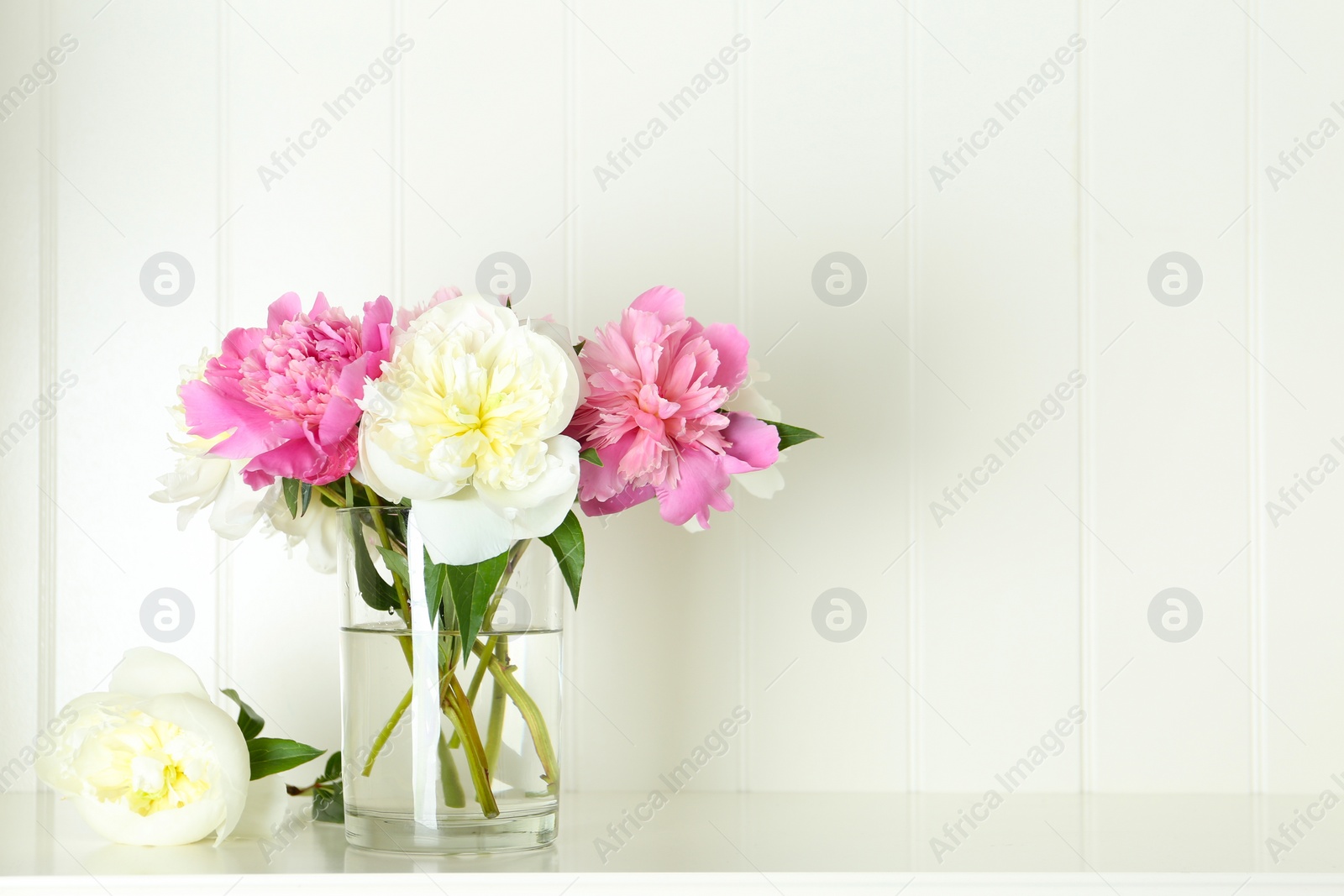 Photo of Bouquet of beautiful peonies in vase on white table. Space for text