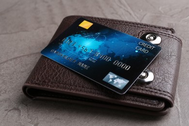 Credit card and leather wallet on grey textured table, closeup