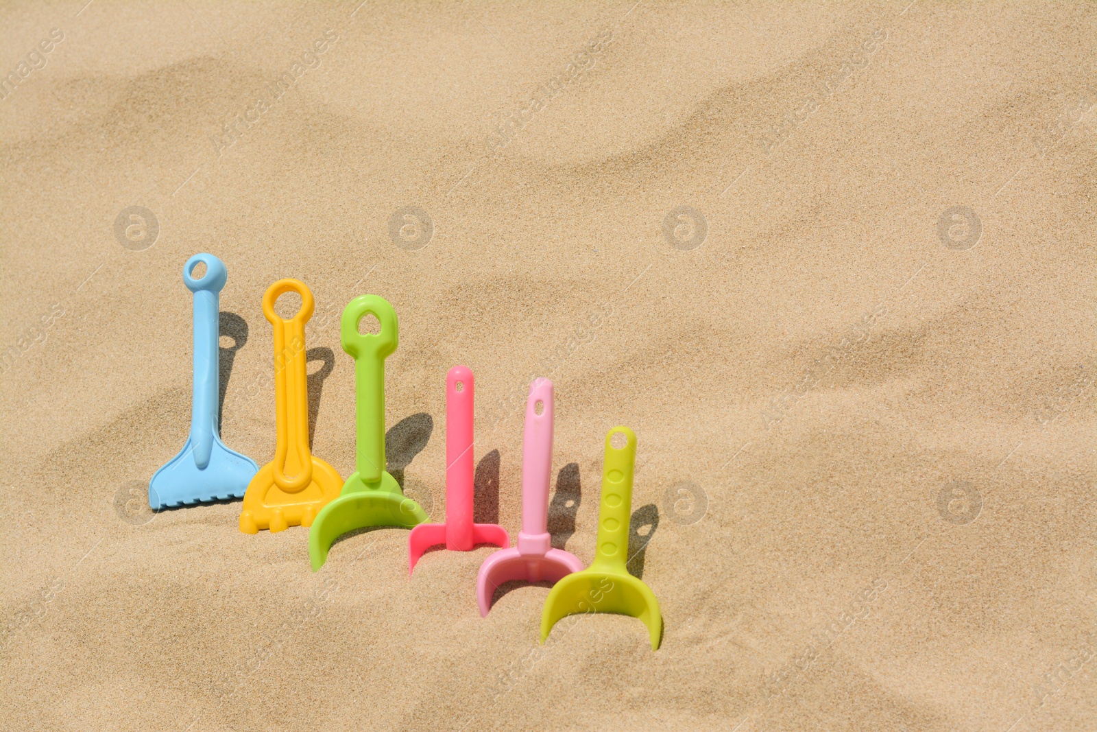 Photo of Set of colorful beach toys on sand. Space for text