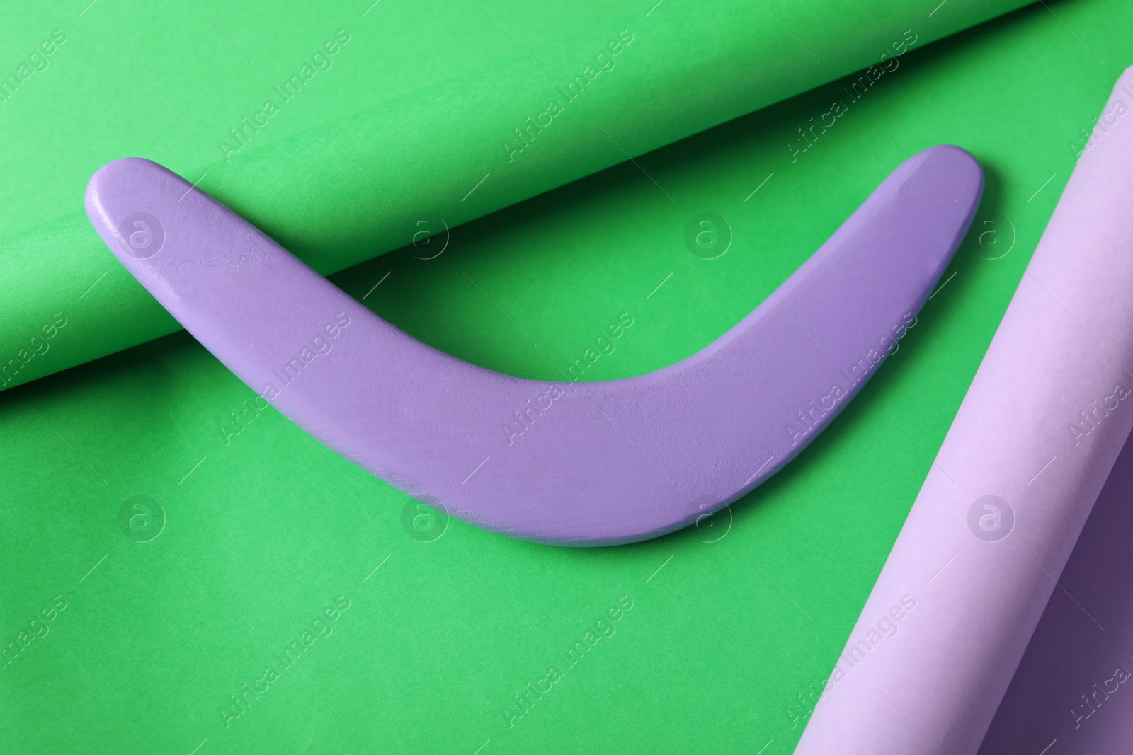 Photo of Lilac wooden boomerang on green background. Outdoor activity