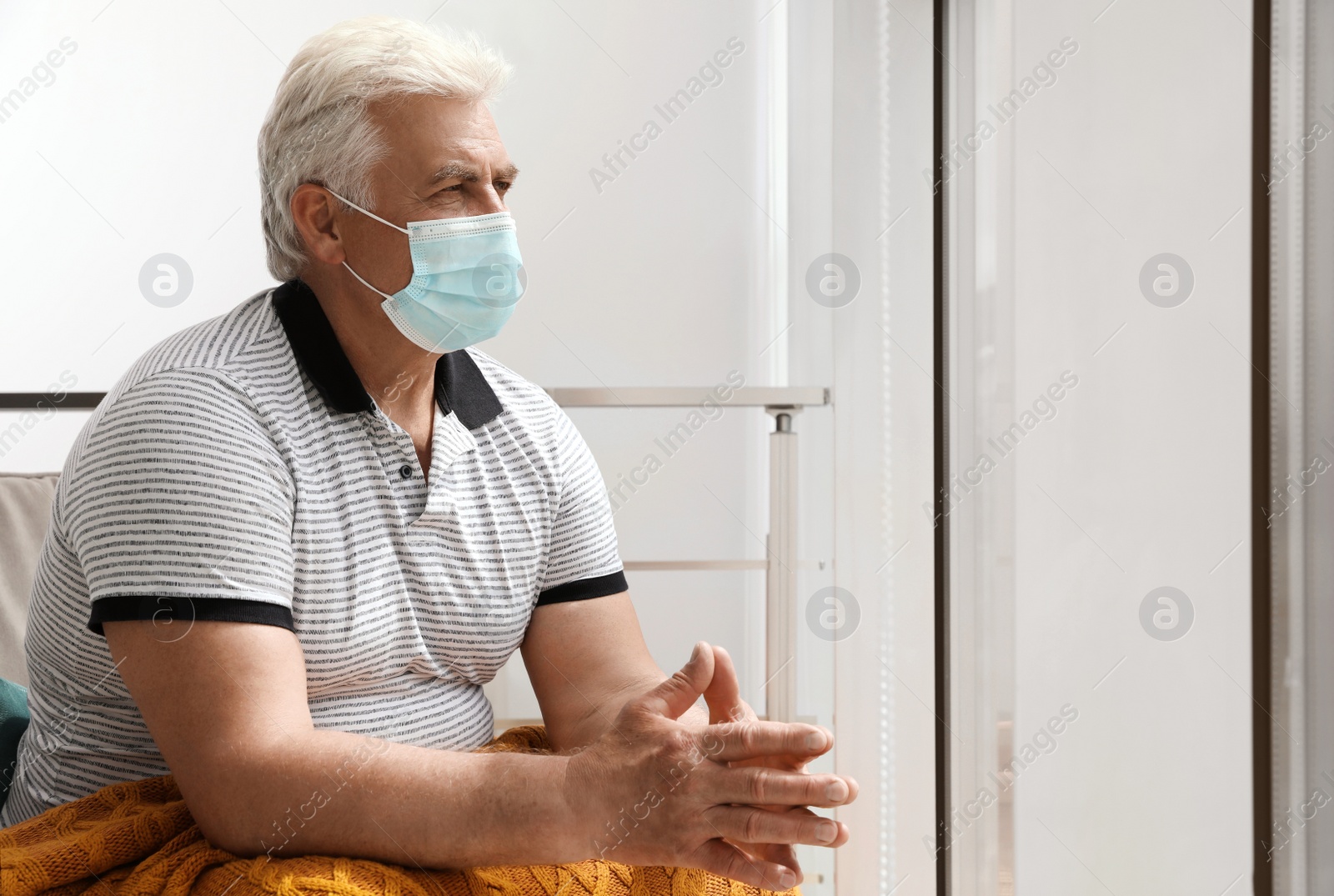 Photo of Senior man with protective mask resting in armchair at nursing home