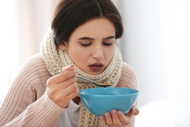 Photo of Sick young woman eating soup to cure flu