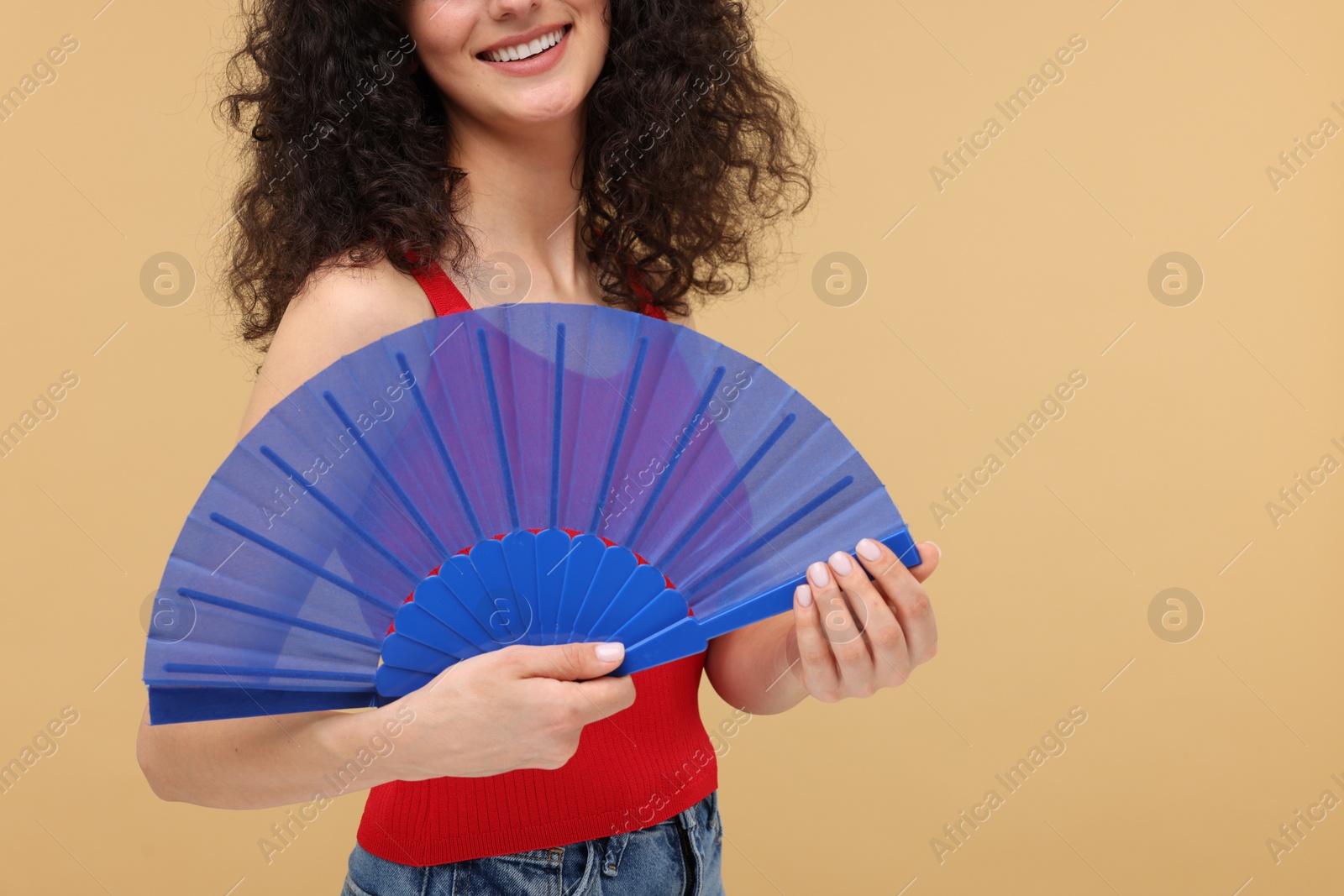 Photo of Woman holding hand fan on beige background, closeup. Space for text