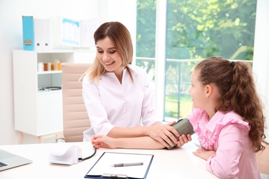 Doctor checking little girl's pulse in hospital