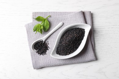 Photo of Black sesame seeds and green leaf on white table, top view