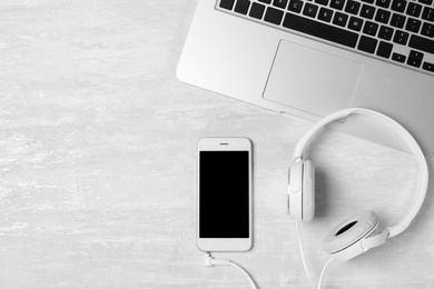 Photo of Flat lay composition with headphones, smartphone, laptop and space for text on light background