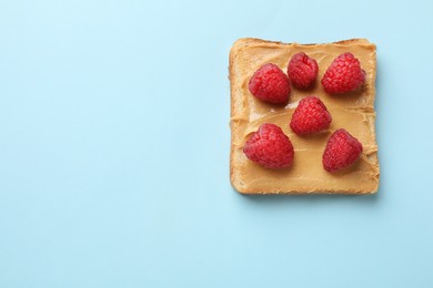 Photo of Tasty peanut butter sandwich with fresh raspberries on light blue background, top view. Space for text