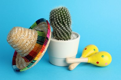 Photo of Mexican sombrero hat, cactus and maracas on light blue background