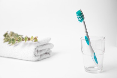 Photo of Light blue toothbrush in glass holder on white background, space for text