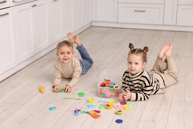 Photo of Cute little children playing together on warm floor in kitchen. Heating system